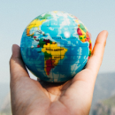 A hand holding a globe